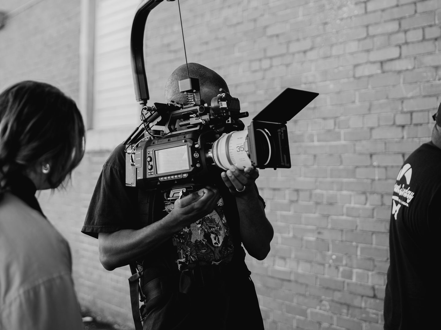 Get Reel WKND camera operator lining up a shot against a brick wall