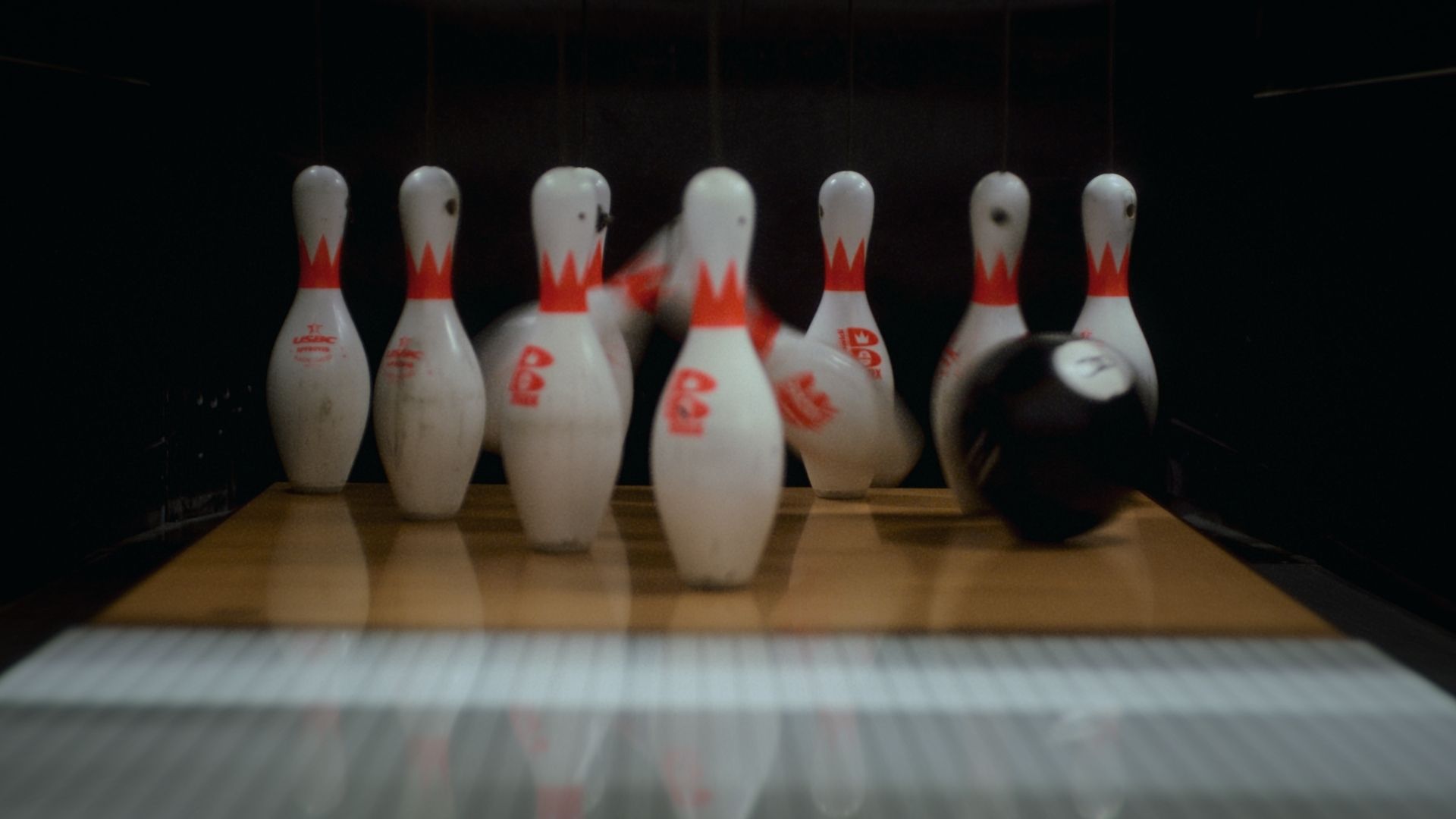 Still from The Long Game: a bowling ball crashes into the pins